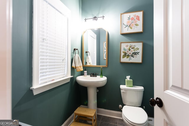 half bath with a sink, tile patterned floors, toilet, and baseboards