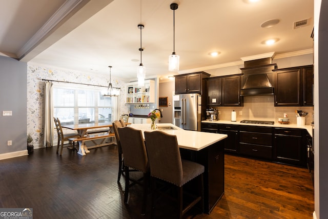 kitchen featuring a breakfast bar, dark wood finished floors, light countertops, appliances with stainless steel finishes, and a sink