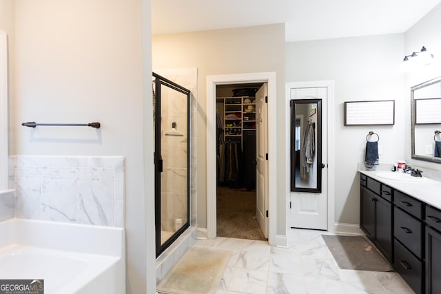 full bathroom featuring marble finish floor, a spacious closet, a stall shower, vanity, and a bath