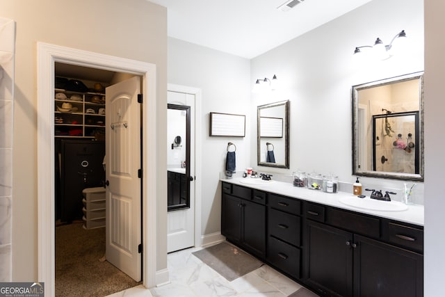 full bath featuring marble finish floor, a shower stall, a walk in closet, and a sink