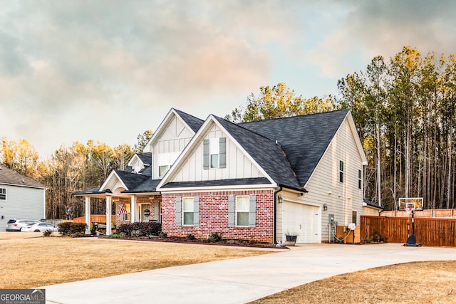 view of front of home featuring a garage, brick siding, fence, driveway, and board and batten siding