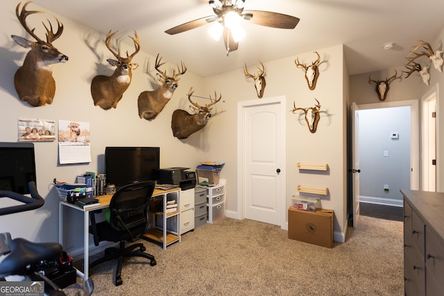 office space featuring a ceiling fan, light carpet, and baseboards