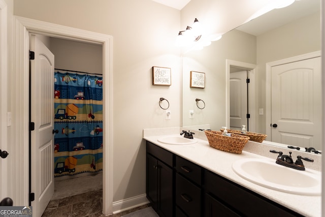 bathroom with a sink, baseboards, and double vanity