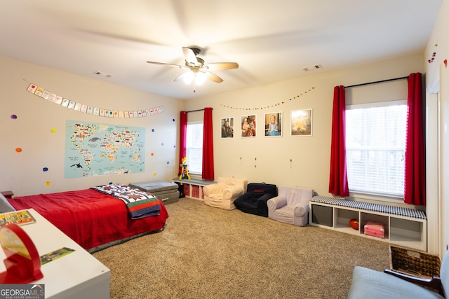 carpeted bedroom featuring ceiling fan, multiple windows, and visible vents