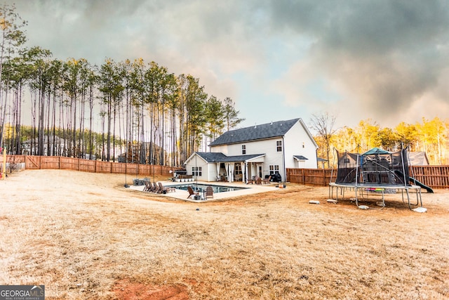 back of property featuring a patio, a trampoline, a fenced backyard, and a fenced in pool