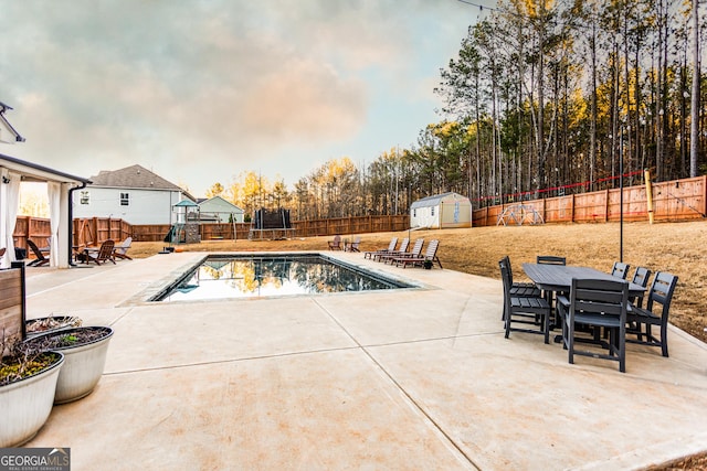 view of pool featuring a storage unit, a fenced backyard, a patio area, and outdoor dining space