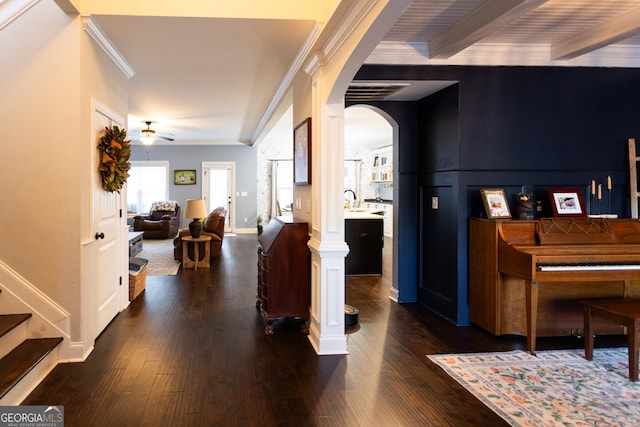 entrance foyer featuring arched walkways, dark wood-style flooring, a ceiling fan, beamed ceiling, and crown molding