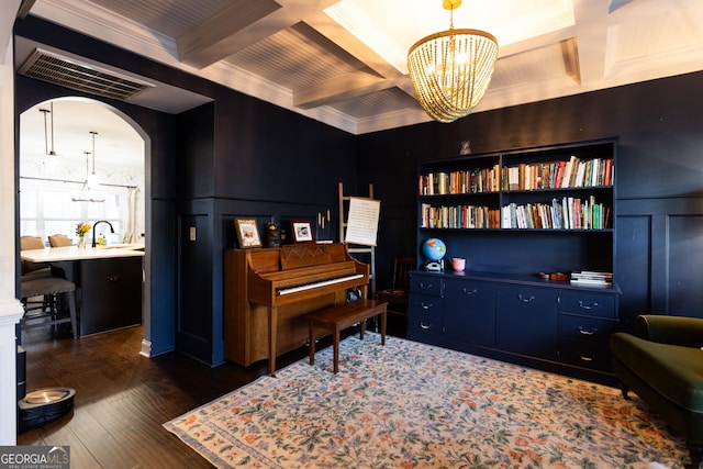 living area featuring arched walkways, beamed ceiling, dark wood-style flooring, and coffered ceiling