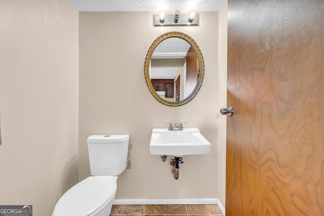 bathroom with toilet, baseboards, and a sink