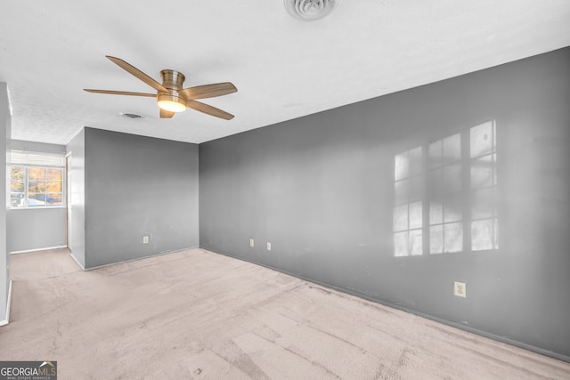 carpeted spare room featuring visible vents and ceiling fan