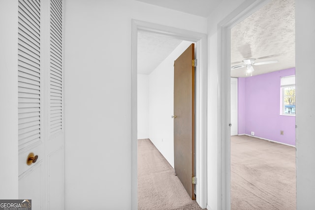 hall featuring carpet floors and a textured ceiling