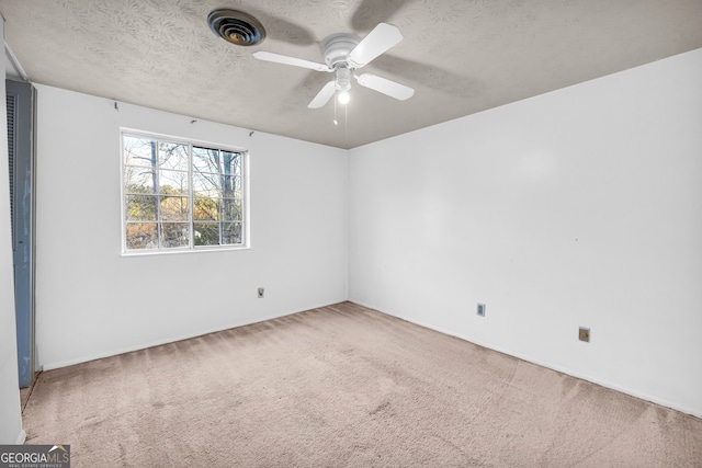 spare room with visible vents, carpet, a ceiling fan, and a textured ceiling