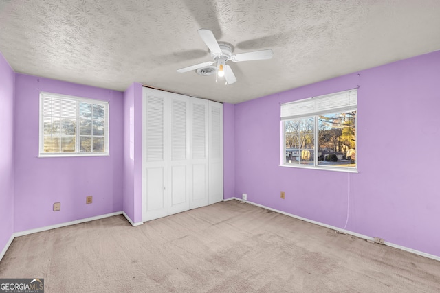 unfurnished bedroom featuring a closet, a ceiling fan, carpet flooring, and a textured ceiling