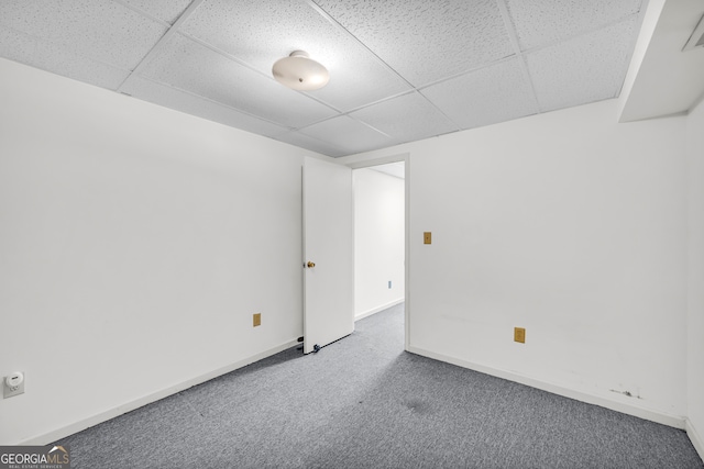 spare room featuring carpet flooring, a paneled ceiling, and baseboards