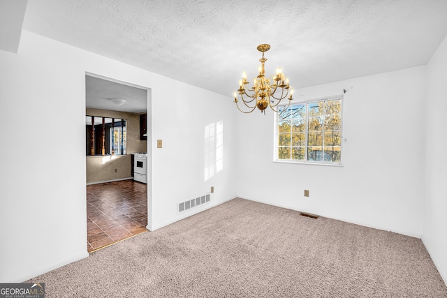 spare room with visible vents, a textured ceiling, a chandelier, and carpet flooring