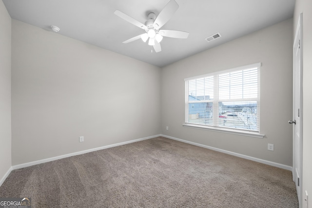 carpeted spare room with ceiling fan, visible vents, and baseboards