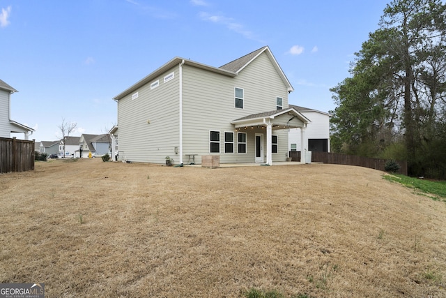 back of property with fence, a lawn, and a patio