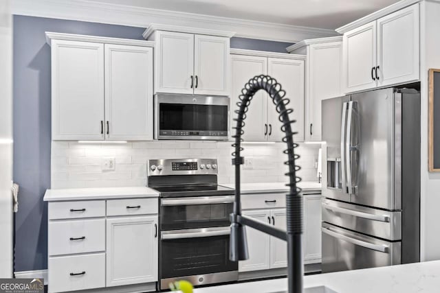 kitchen with white cabinets, decorative backsplash, ornamental molding, stainless steel appliances, and light countertops