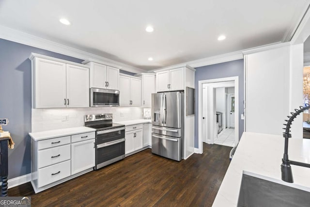 kitchen with dark wood-style floors, light countertops, backsplash, appliances with stainless steel finishes, and ornamental molding