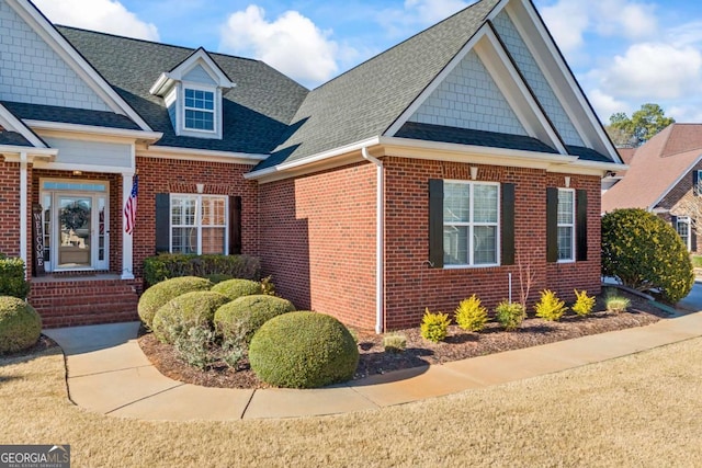 view of front of home with roof with shingles and brick siding