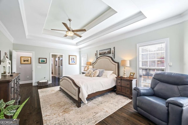 bedroom featuring ornamental molding, a tray ceiling, dark wood-style flooring, and baseboards