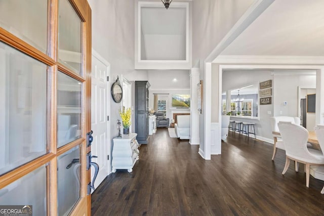 entrance foyer with baseboards, dark wood-style flooring, decorative columns, and a notable chandelier