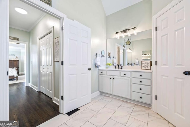 ensuite bathroom featuring marble finish floor, ornamental molding, connected bathroom, vanity, and baseboards