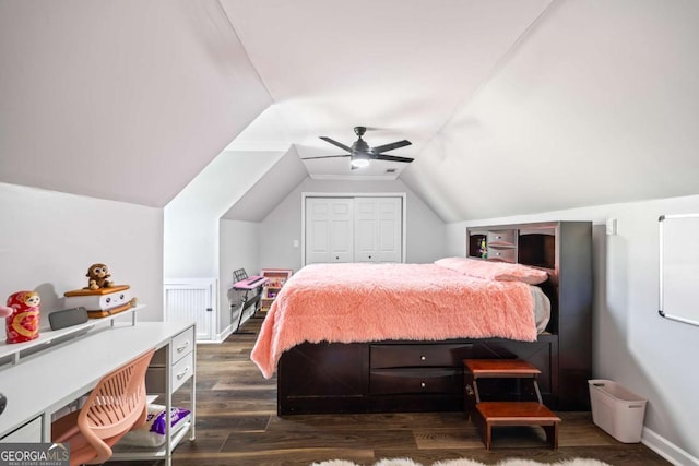 bedroom featuring lofted ceiling, dark wood-style flooring, a ceiling fan, baseboards, and a closet