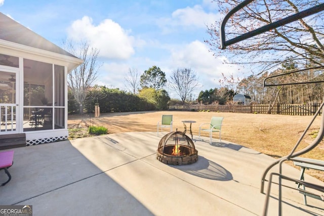 view of patio / terrace with a sunroom, fence, and a fire pit