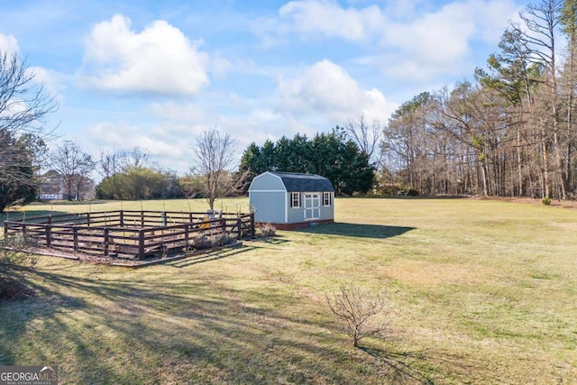 view of yard featuring a storage unit, a rural view, fence, and an outbuilding