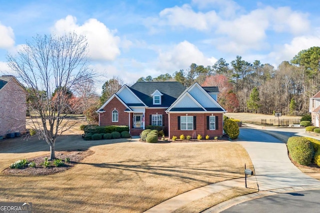 traditional-style house with a front yard, concrete driveway, and brick siding