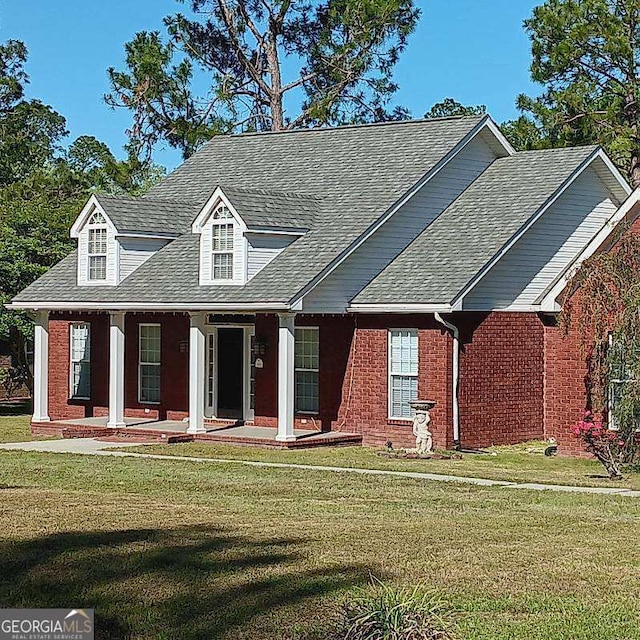view of front of property featuring brick siding, a porch, roof with shingles, and a front lawn