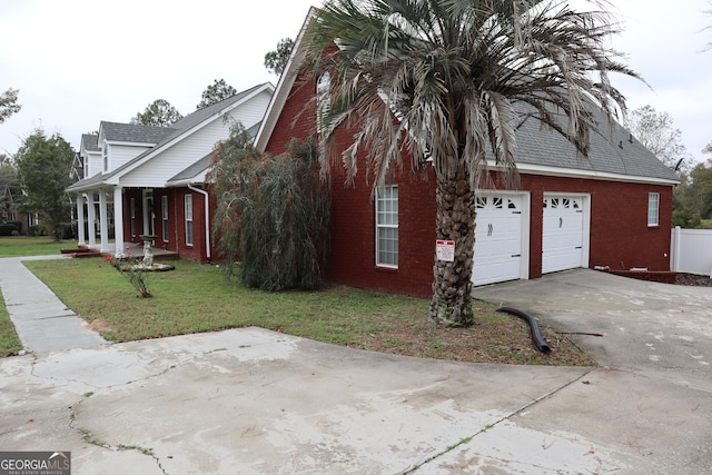 view of property exterior with a yard, brick siding, and driveway