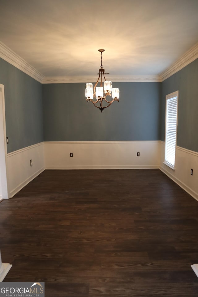 empty room with a chandelier, ornamental molding, dark wood-style flooring, and wainscoting