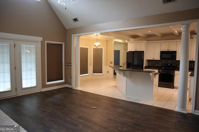 kitchen with black appliances, visible vents, decorative columns, and dark countertops