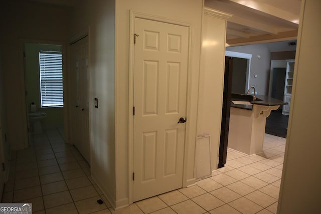 hallway with light tile patterned flooring, a sink, and visible vents