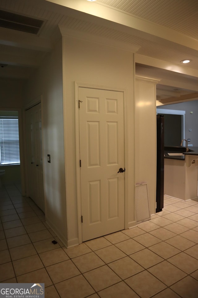 corridor with beam ceiling, visible vents, a sink, and light tile patterned floors