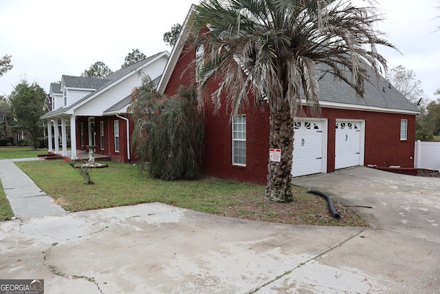 view of side of property with a garage, concrete driveway, brick siding, and a yard