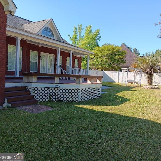 rear view of property featuring fence and a lawn