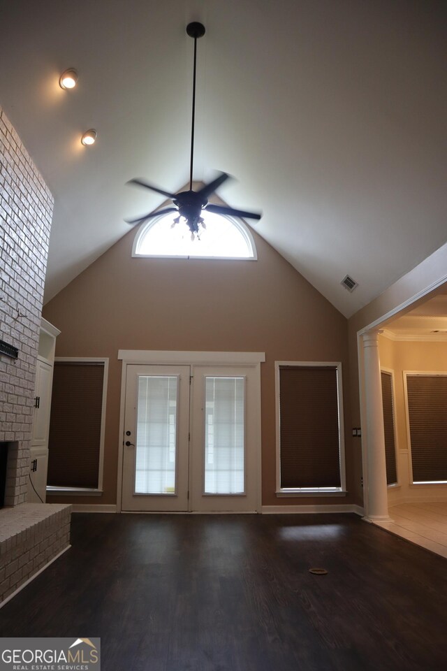 unfurnished living room with high vaulted ceiling, a ceiling fan, a brick fireplace, and dark wood-style floors