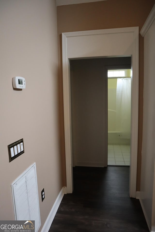 hall featuring dark wood-style flooring, visible vents, and baseboards