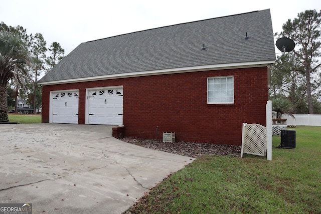 view of property exterior with central AC unit, a garage, brick siding, roof with shingles, and a lawn