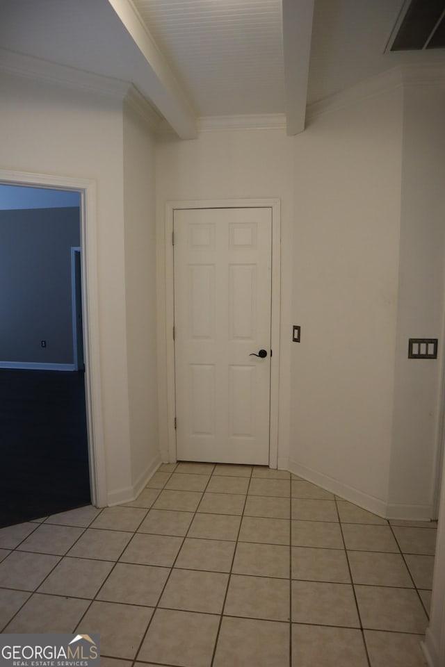 hallway with light tile patterned floors, ornamental molding, visible vents, baseboards, and beam ceiling