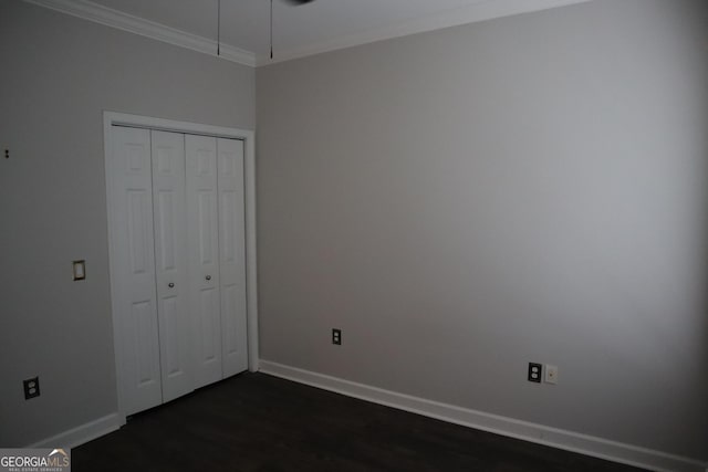 unfurnished bedroom with dark wood-type flooring, ornamental molding, a closet, and baseboards