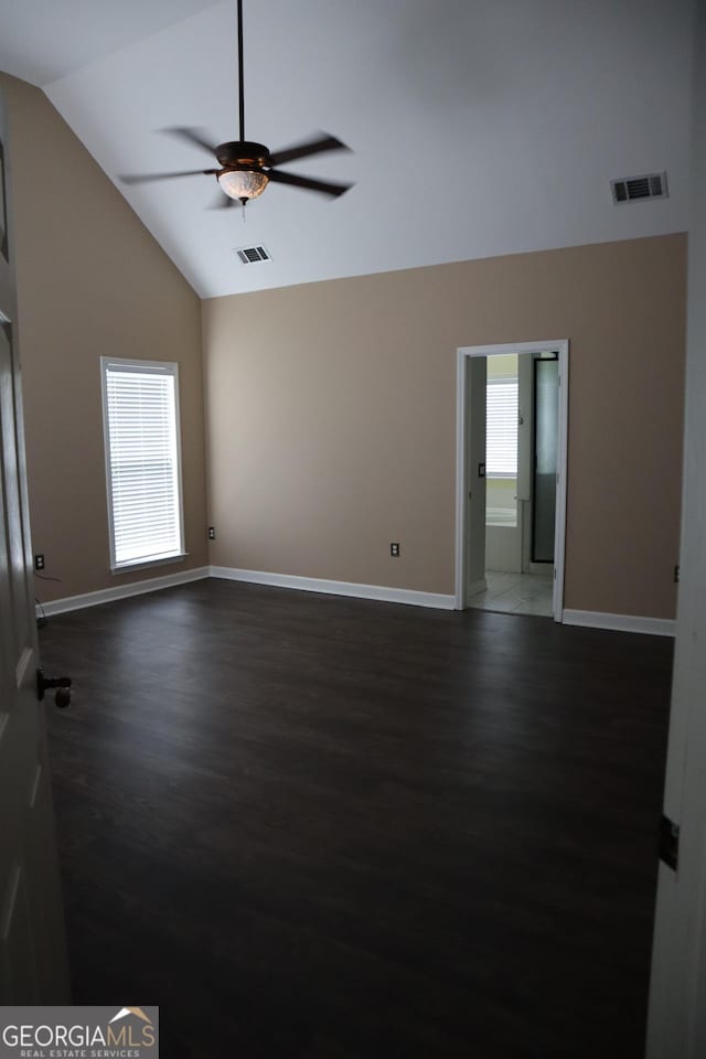 empty room featuring plenty of natural light, dark wood finished floors, and visible vents