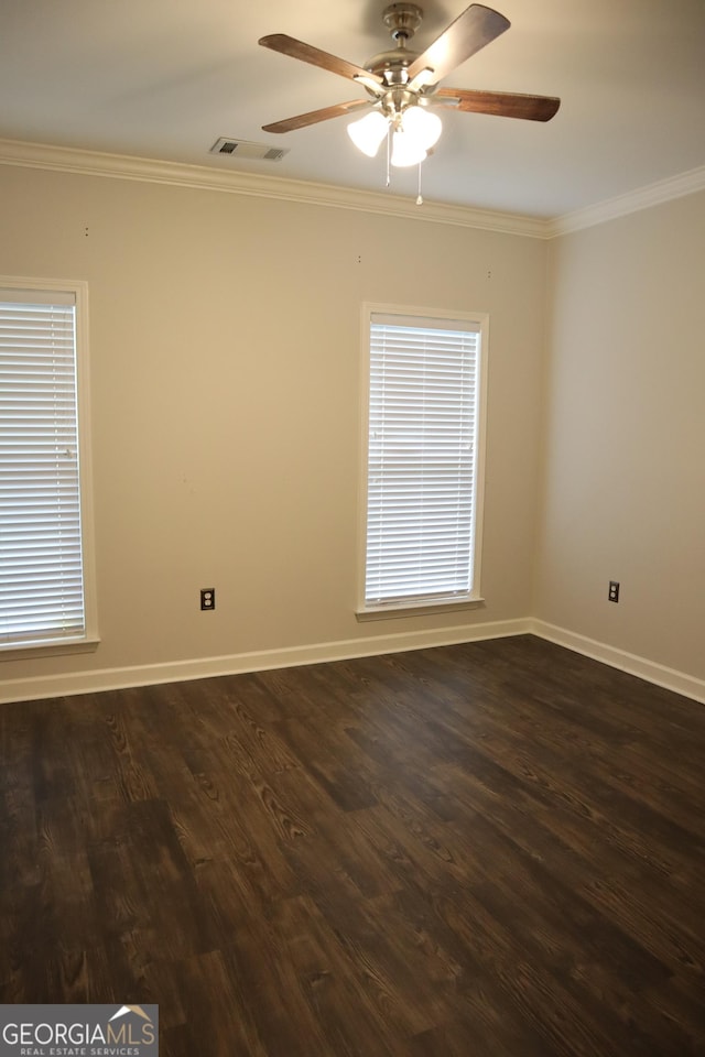 spare room featuring crown molding, a ceiling fan, visible vents, baseboards, and dark wood-style floors