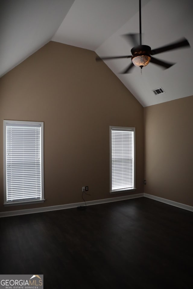 spare room with lofted ceiling, ceiling fan, dark wood-type flooring, visible vents, and baseboards