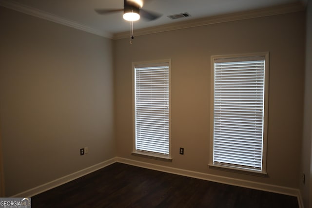 spare room featuring dark wood-style flooring, baseboards, crown molding, visible vents, and ceiling fan