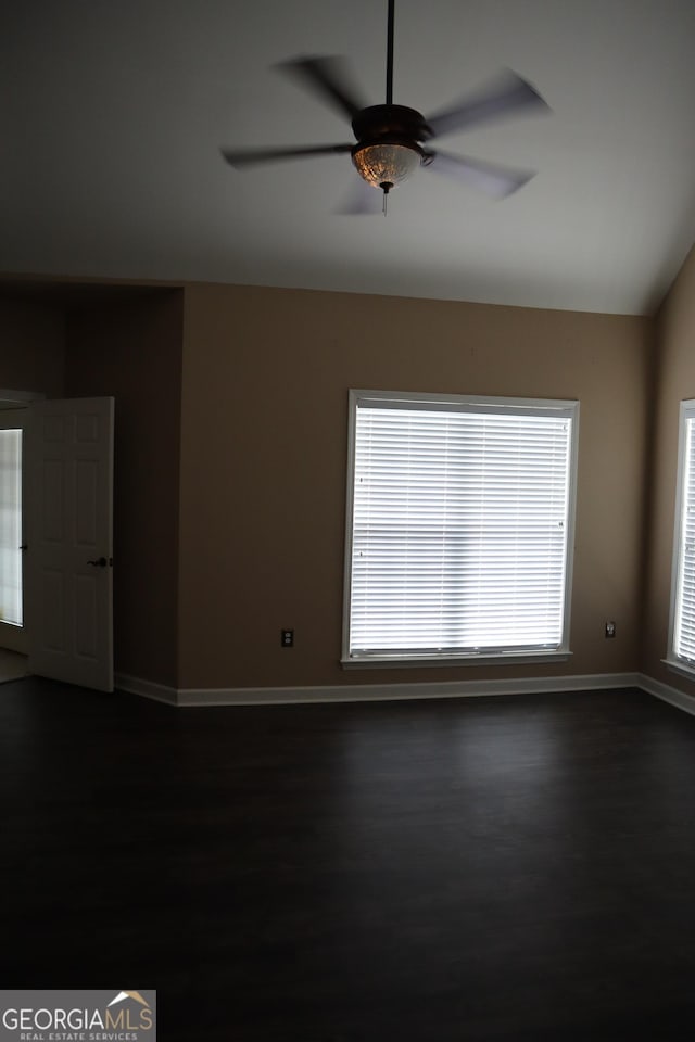 unfurnished room featuring vaulted ceiling, dark wood-style floors, baseboards, and a ceiling fan