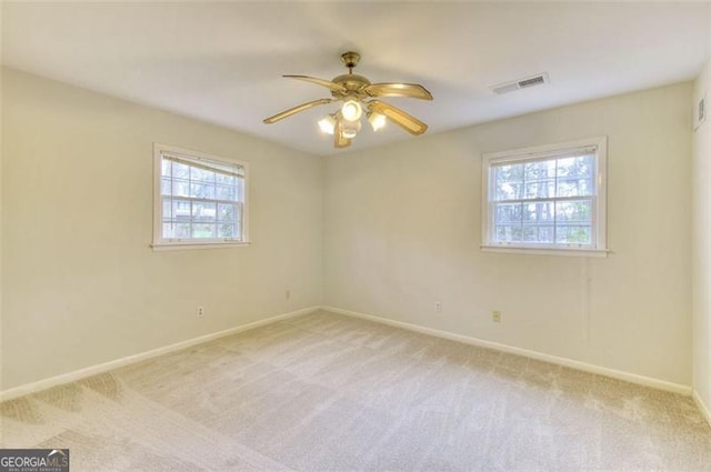 carpeted empty room featuring baseboards, visible vents, and a ceiling fan